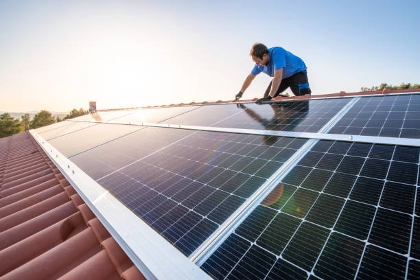 Professional worker installing solar panels on the roof of a house. stock photo